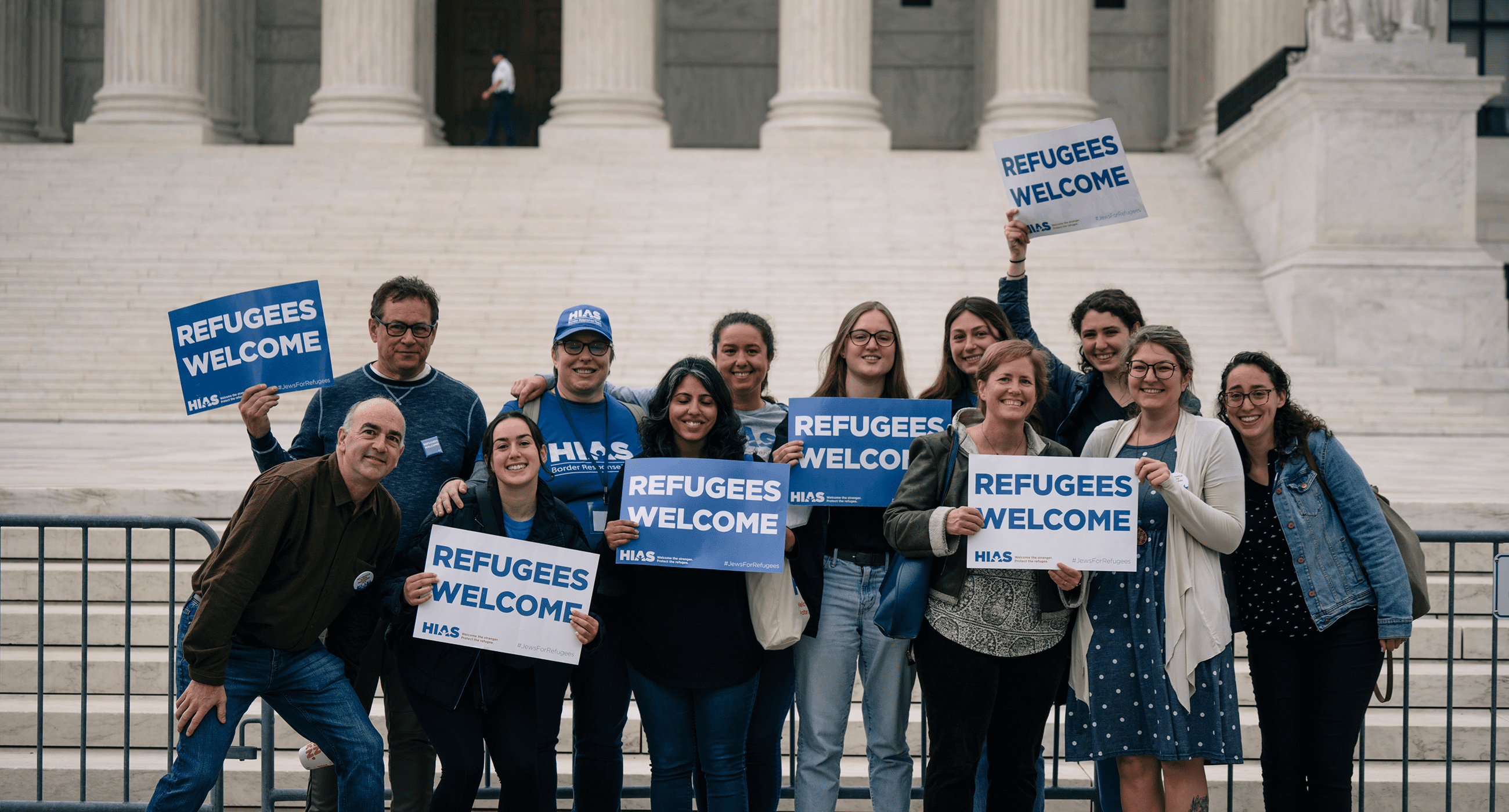 Staff and supporters of HIAS hold signs that read "Refugees Welcome" in front of the U.S. Supreme Court.